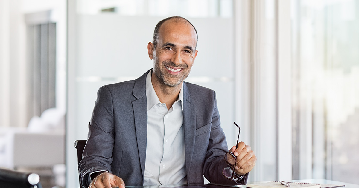 Successful senior businessman sitting in meeting room with phone and tablet.