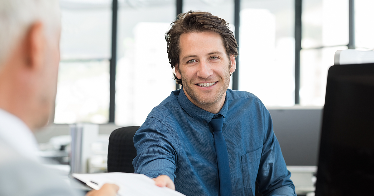 Close up of young businessman giving writing pad to senior businessman.