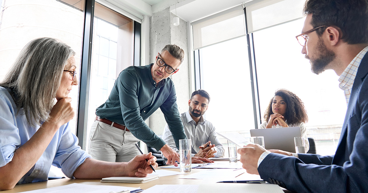 Male mature ceo businessman leader with diverse coworkers team working together on project in boardroom