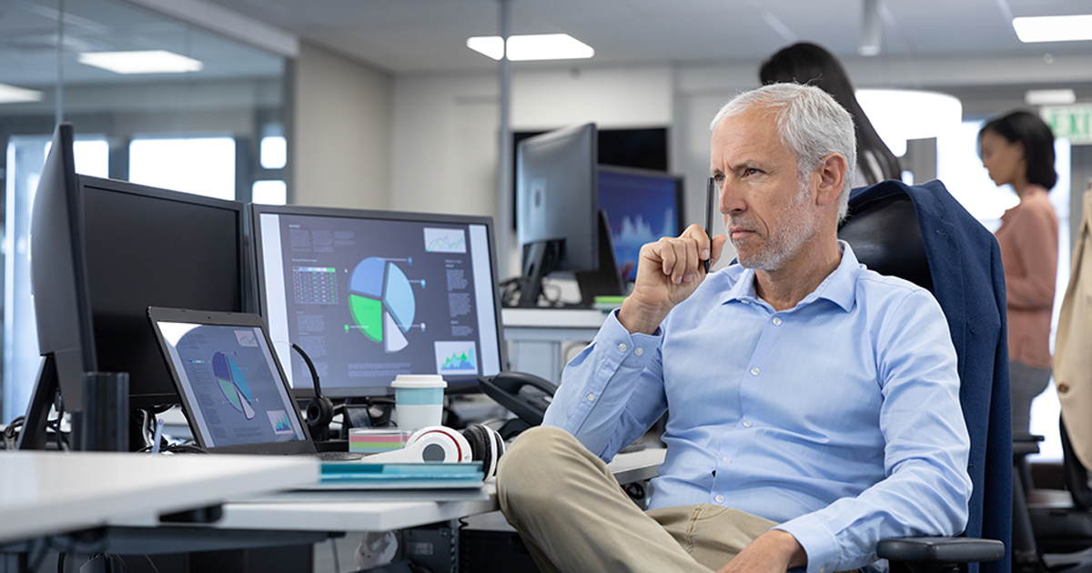 businessman working in a modern office, sitting at desk using computers, thinking.
