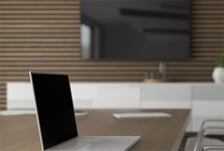 close up of a laptop on a table with a tv in the background