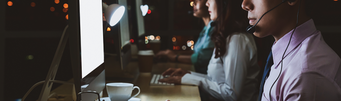 Employee working in front of computer at desk during night shift. 