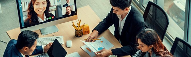 A group of business professionals have a video conference call with a remote team.