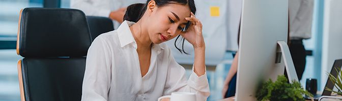 Business woman looks frustrated while sitting in front of a computer.