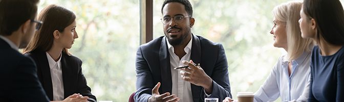 A small business owner talks to their team during a meeting.