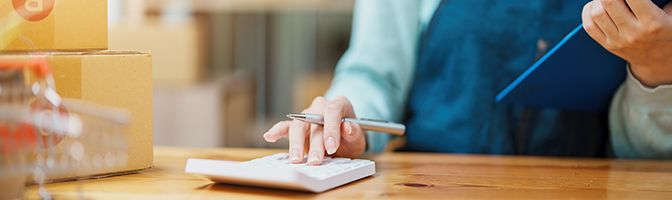 A small business person does some accounting using a calculator.