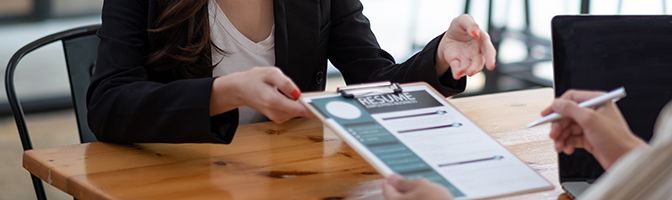 A hiring manager hands a form to a potential job candidate.