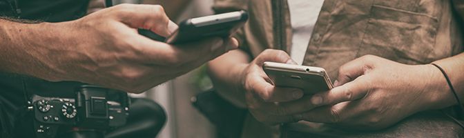 Closeup of the hands of two people doing a search through their mobile devices.