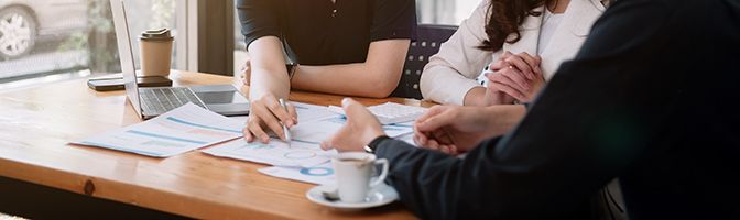 Small business owners go over financing strategies during a discussing while sitting around a table.