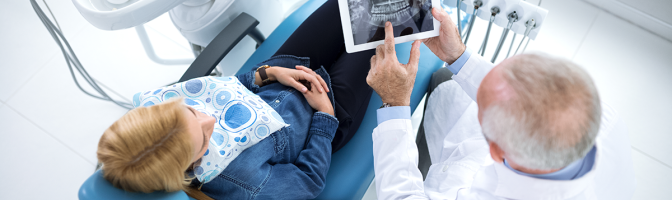 Dentist and patient looking at x-ray of teeth in a dentist's office