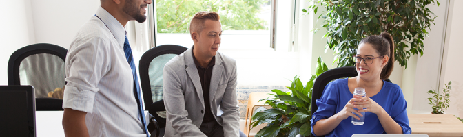 Cheerful businesswoman talking to employees giving tasks or listening to report.
