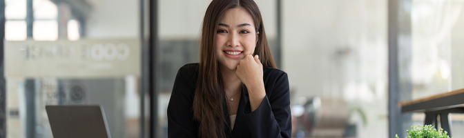 Young businesswoman working at desk smiling with computer laptop on desk.