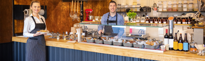 Counter service at modern bistro with smiling waiters serving food 