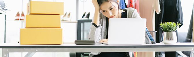 Business owner sits at a desk looking at a laptop in frustration.