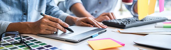 A closeup to a desk where business associates are looking over branding documents.