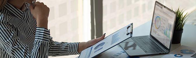 A person looking at a clipboard at a desk.