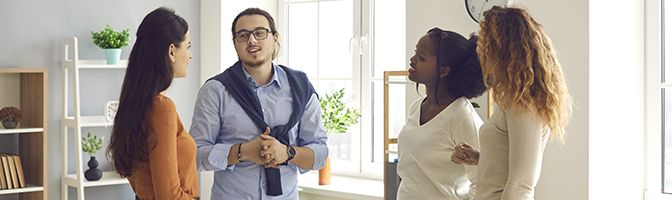 A group of four people stand in a circle while having a discussion.