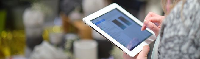 Closeup of a business owner scrolling through information on a tablet device.