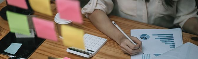 Small Business Owners looking over financial documents with a calculator next to her.