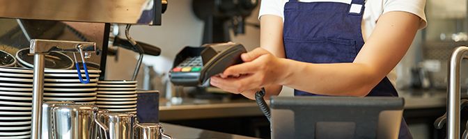 A person holds up a credit card processing machine.