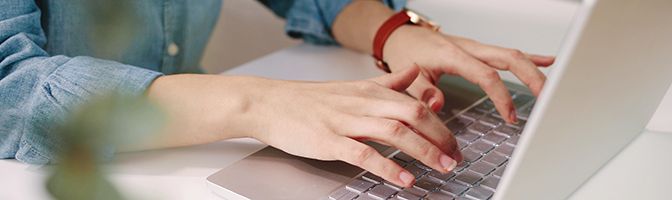 Image of hands typing on a laptop.