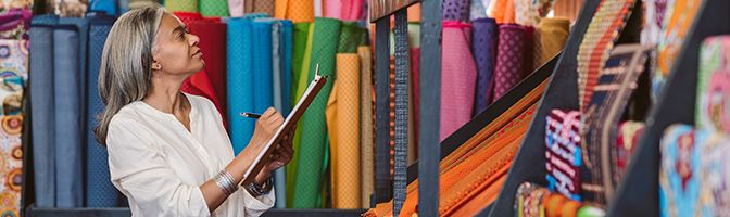 Small business owner performing a supply check on inventory of fabric available at store.