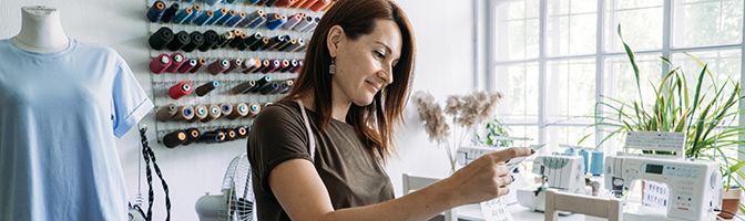 A small business owner looks at a tablet while in their store.