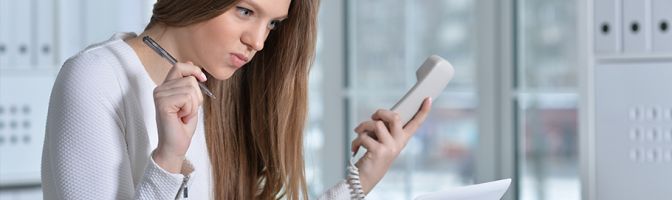 business woman using a traditional desk phone at work