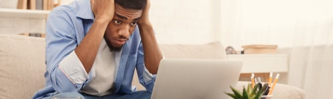 Man holding head in his hands while viewing laptop