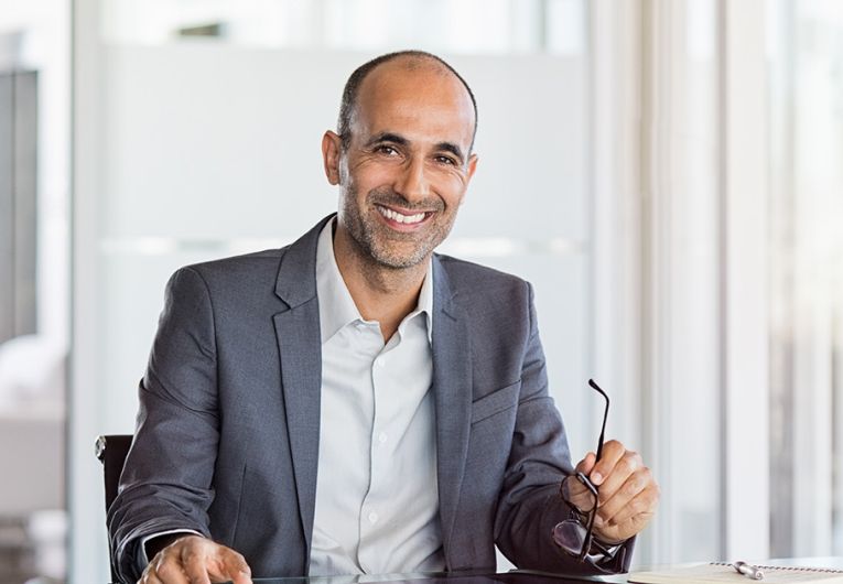 Successful senior businessman sitting in meeting room with phone and tablet.