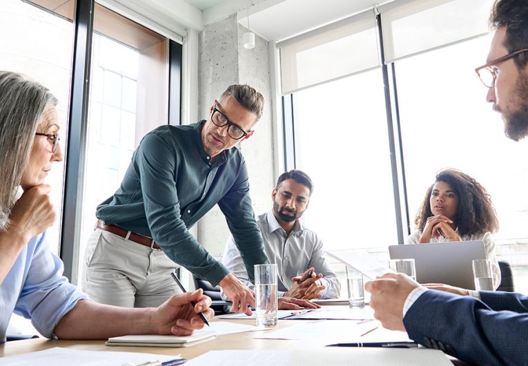 Male mature ceo businessman leader with diverse coworkers team working together on project in boardroom