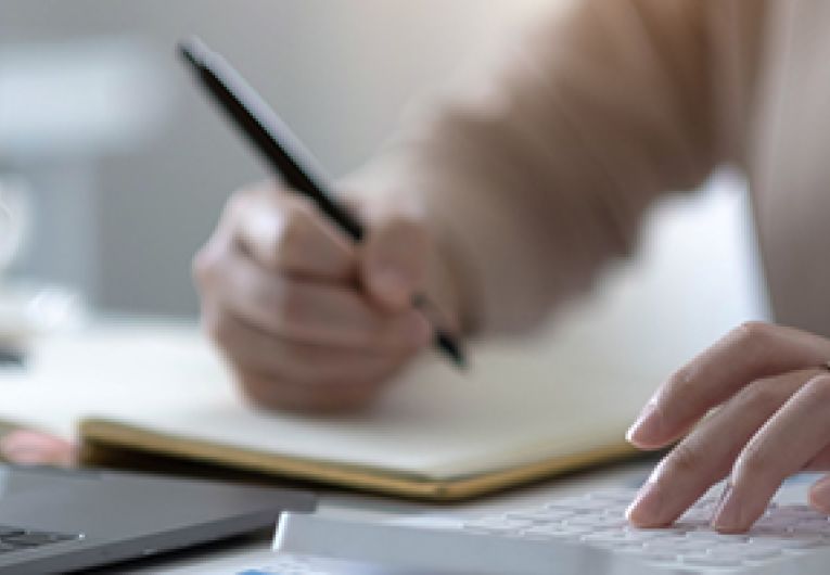 A person writing at a desk.