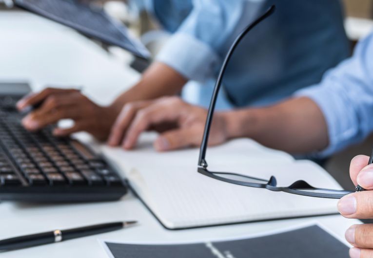 Two people sitting at a desk in front of a lap top.