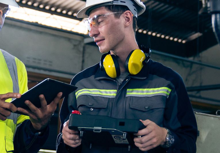 Two people talking while wearing safety paraphenelia.