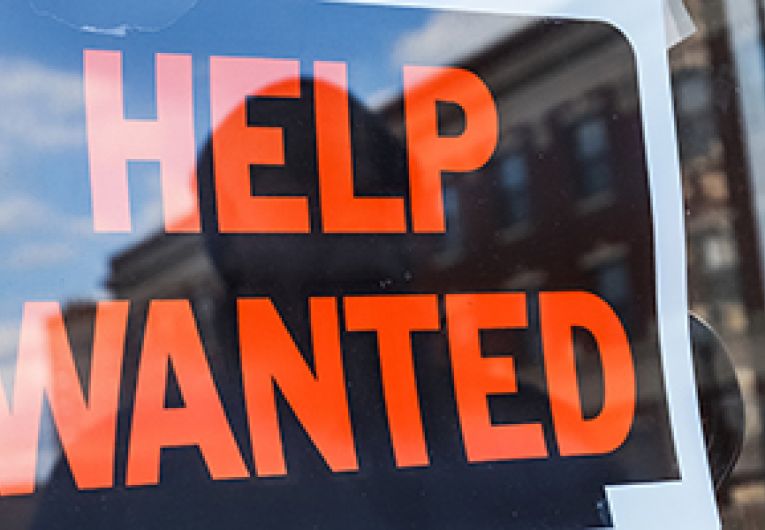Close up of a help wanted sign in the window of a business.