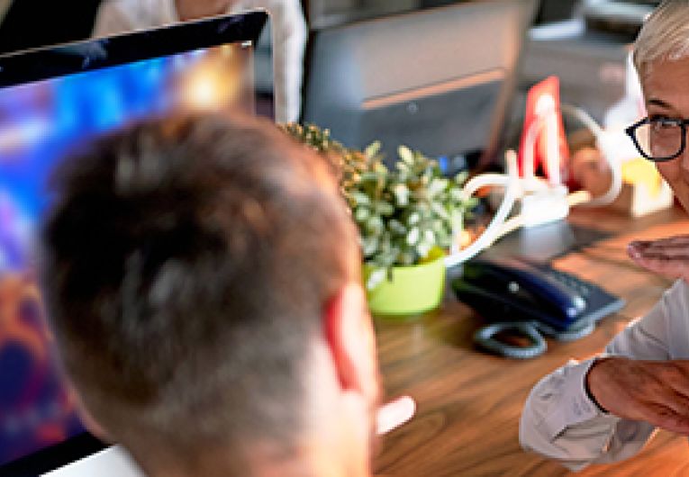 An entrepreneur has a discussion at a desk with their mentor.