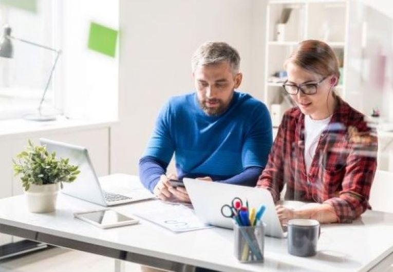 Man and Woman viewing a laptop at office desk