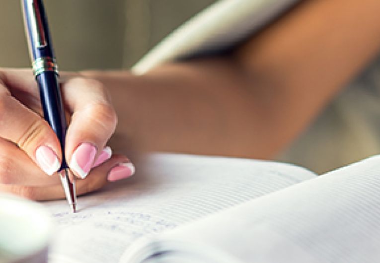 Businesswoman writing in a notebook with a pen.