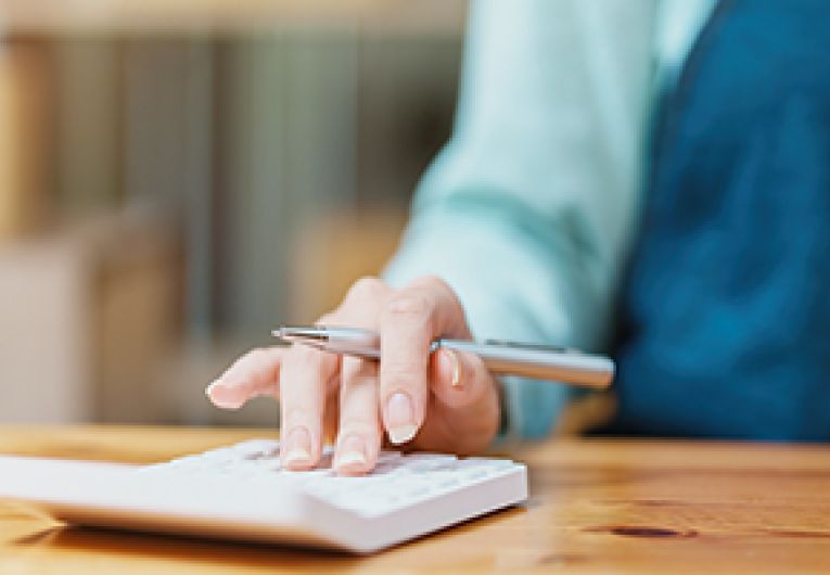 A small business person does some accounting using a calculator.