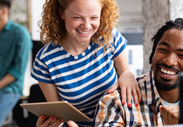 An employee working at a computer while being mentored.