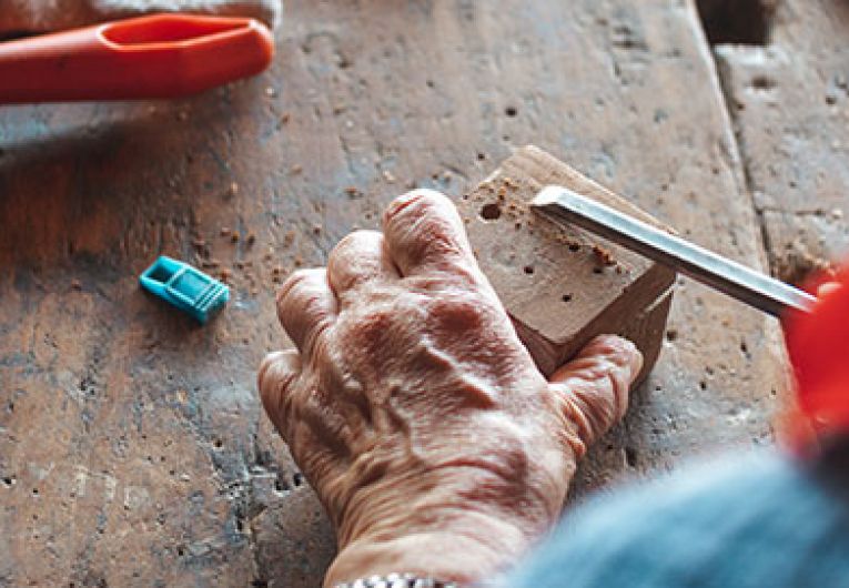 close up of someone using a chisel on a block of wood