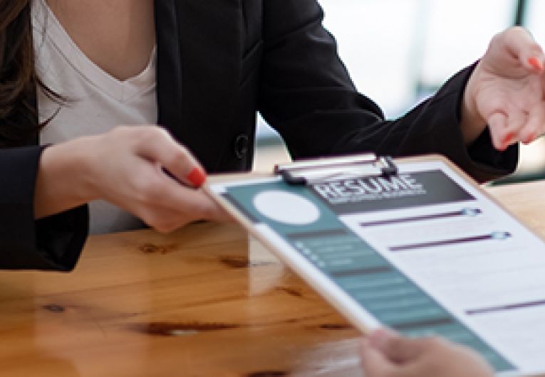 A hiring manager hands a form to a potential job candidate.