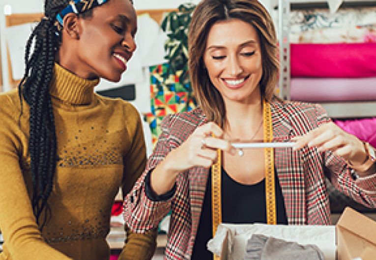 Two small business owners taking a photo of merchandise to sell online.