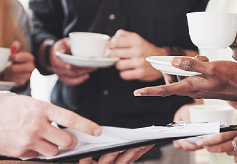 closeup of a stand up meeting with people looking at a tablet