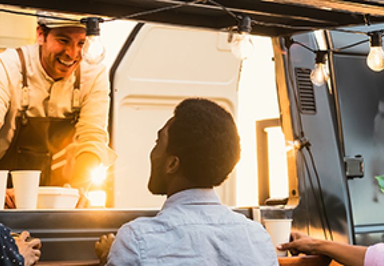 Three people standing at a food truck.