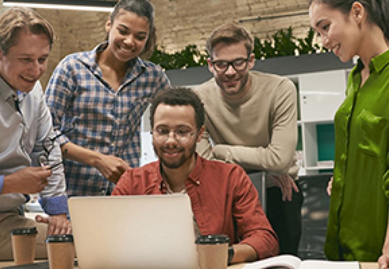 Group of business professionals around a laptop watching a video.