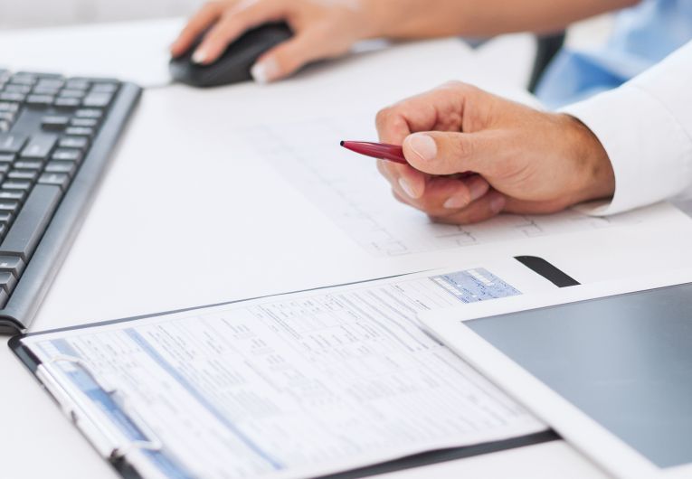 Doctor using tablet and computer to review charts