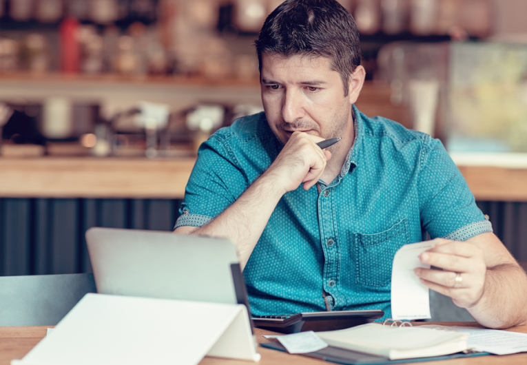 Restaurant owner consulting with AI Chat gpt on a tablet while looking at bills and expenses of his small business.