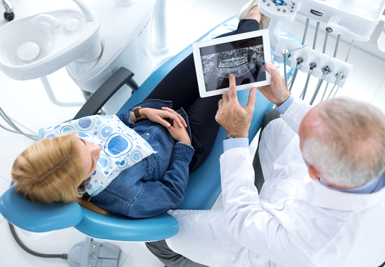 Dentist and patient looking at x-ray of teeth in a dentist's office