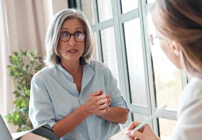 Mature female mentor or manager training young intern explaining sharing professional skills in office.